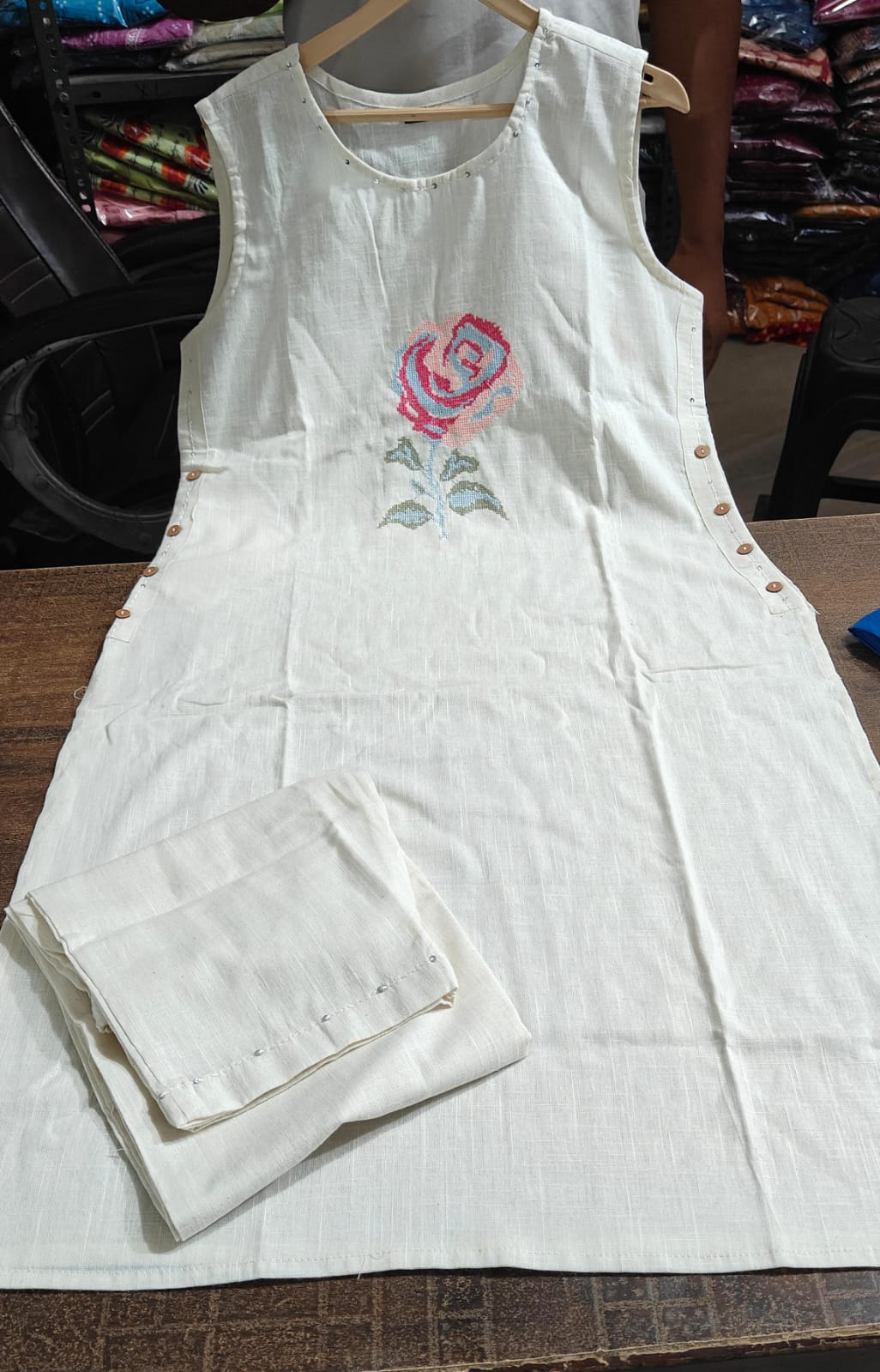 Off-White Sleeveless Cotton Kurti Set with Hand-Embroidered Floral Motif.