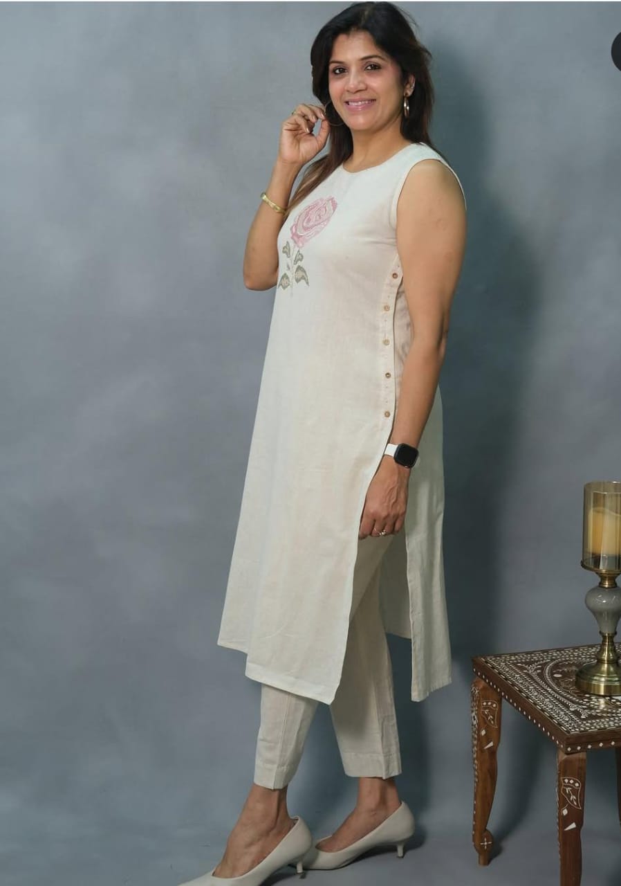 Off-White Sleeveless Cotton Kurti Set with Hand-Embroidered Floral Motif.